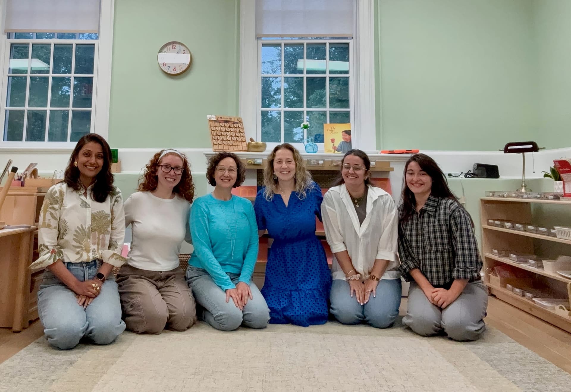 Six Beacon teachers kneeling in a row in the primary classroom