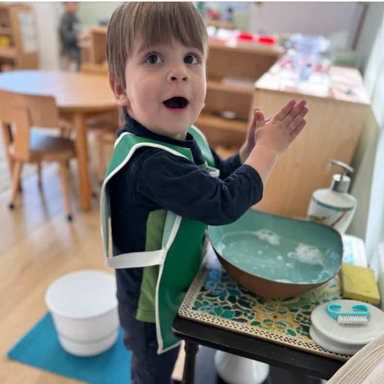A young child washing hands at a Montessori practical-life station